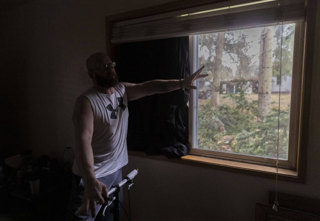 Shawn Hawes talks about barely making it out of bed before part of a tree shattered his window sending glass across his bed on Wednesday, Nov. 20, 2024 in Lake Stevens, Washington. (Olivia Vanni / The Herald)
