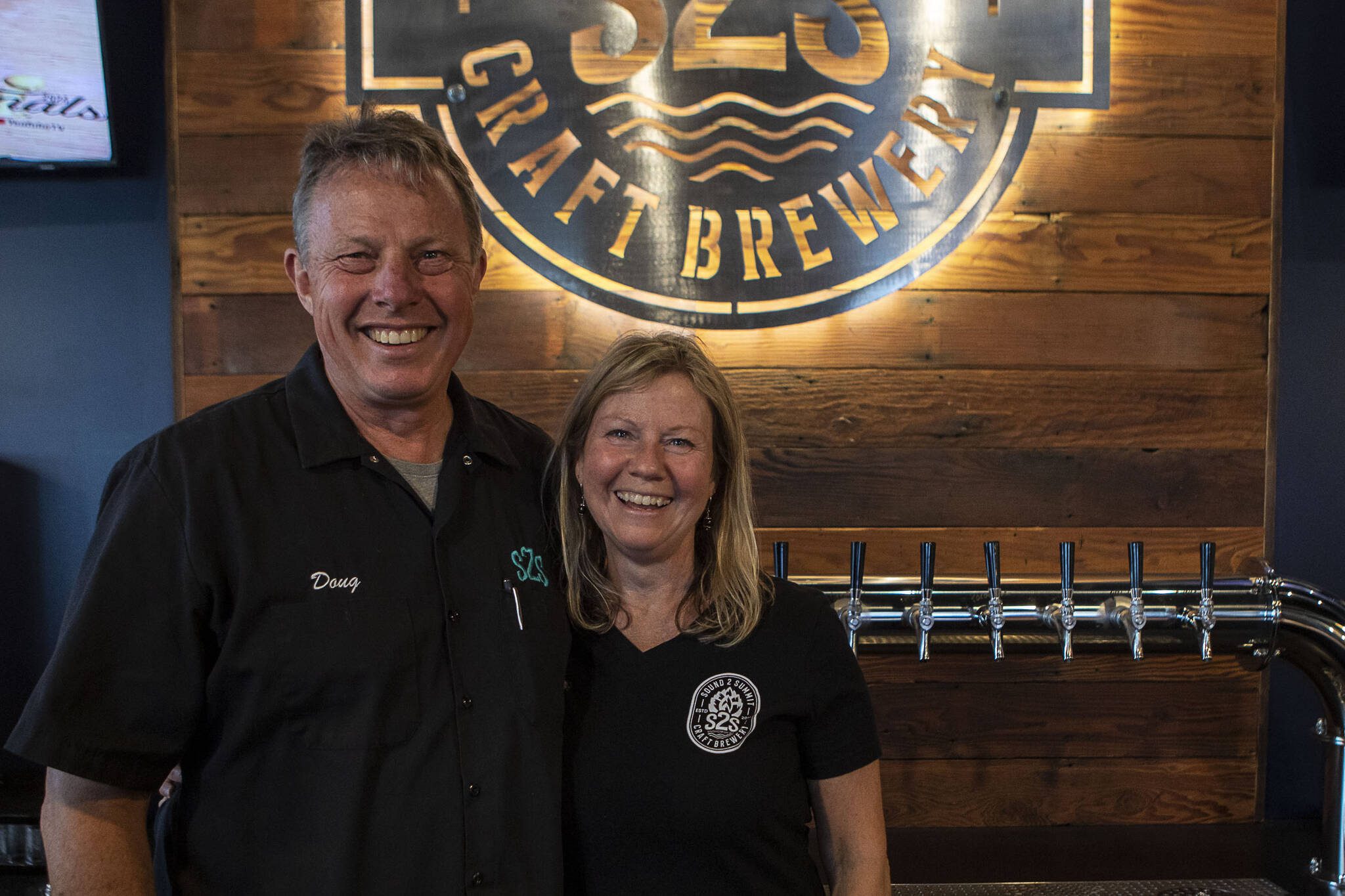 Owners Doug Milnor, left, and Christine Milnor, right, pose for a photo inside the new Sound To Summit Brewing location in Everett, Washington on Friday, June 9, 2023. (Annie Barker / The Herald)